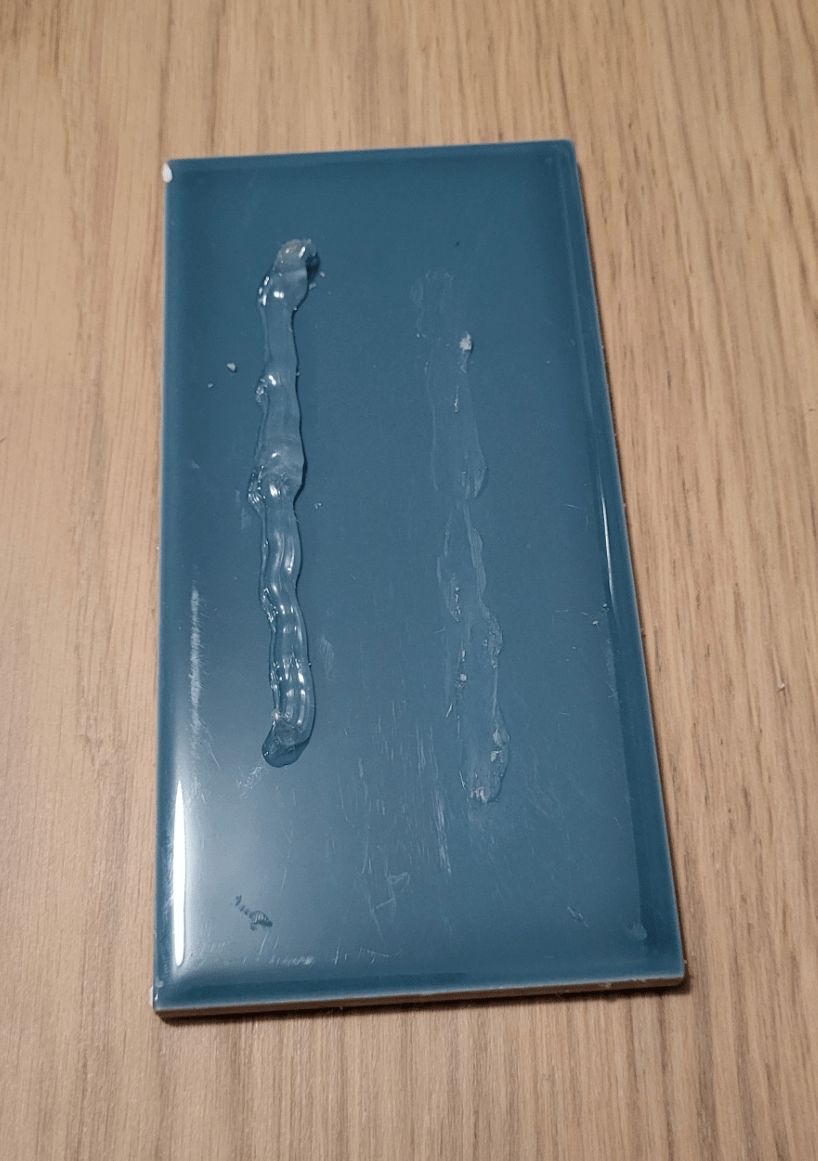 A tile with a bead of silicone caulk that has been removed mechanically.